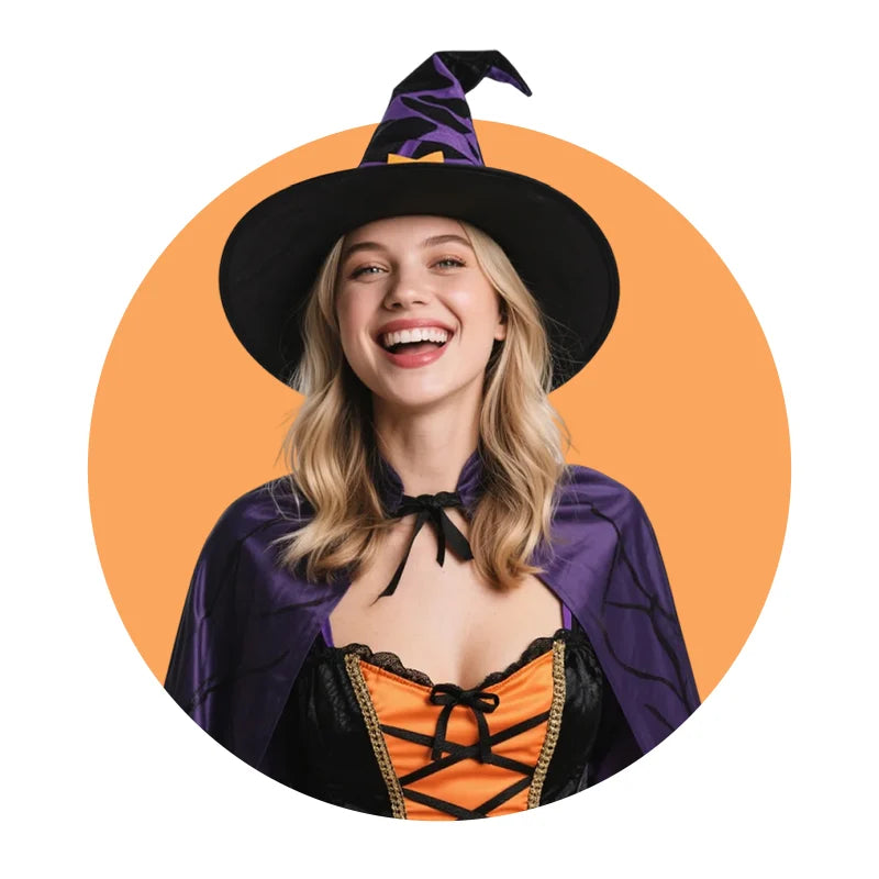 Woman in a black/purple Halloween witch hat & cape, with an orange-accented dress, set against an orange background.
