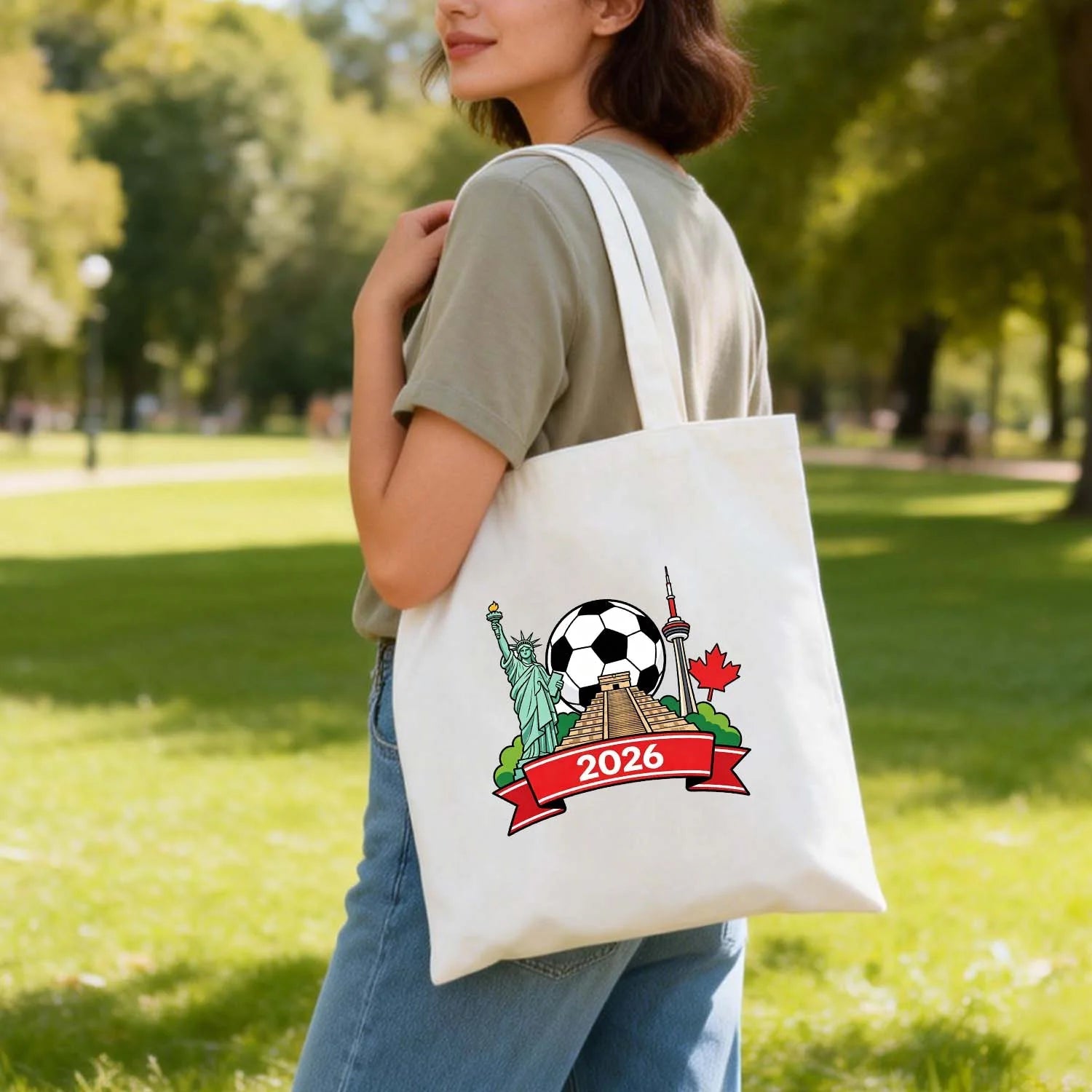 Model carrying 2026 World Cup themed tote bag with USA Statue of Liberty, Mexico pyramid, Canada CN Tower and soccer ball design, cotton canvas bag